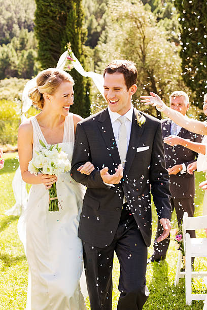 istock Newlywed Couple Walking While Guests Throwing Confetti On Them 175114328