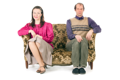 old looking couple having conflict siiting on vintage couch isolated on white