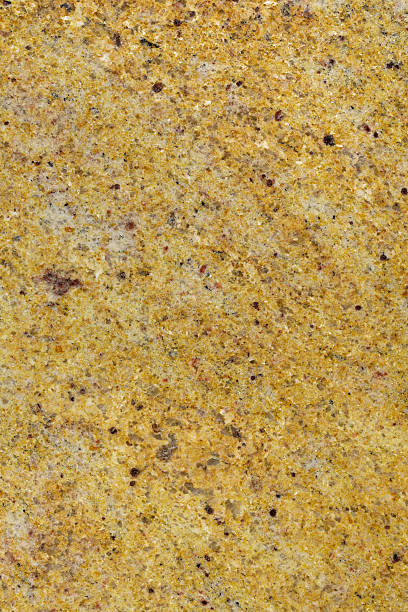 Madura Gold Granite a high definition view of Madura Gold with its fine crystalline content with mixed yellows and gold with distinct red crystals. This type of granite is used extensively for decorative purposes in kitchens, bathrooms, work tops and facades and originates from India. feldspar stock pictures, royalty-free photos & images