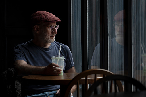 Caucasian man in a coffee shop against window