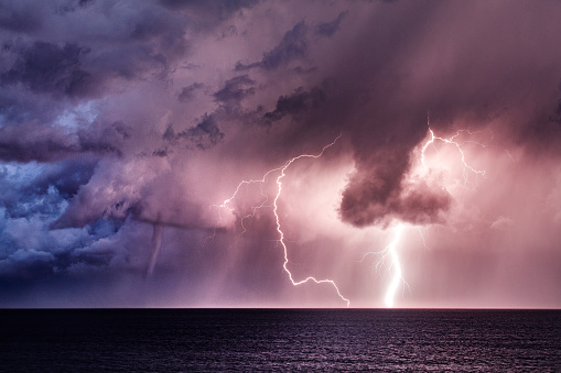 Lightning storm with a tornado waterspout in the ocean.