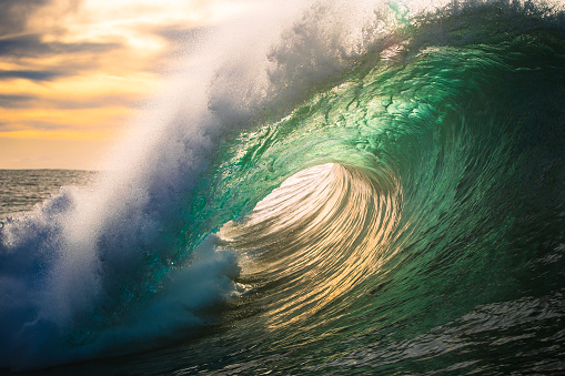 Ocean wave energy breaking over shallow reef in golden light. Photographed off the east coast of Australia.