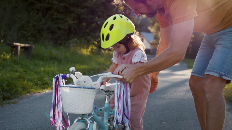 Father preparing his daughter for bike riding training.