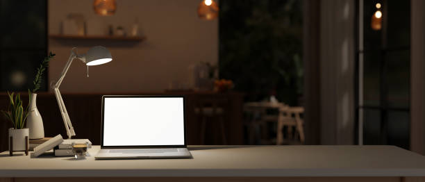 istock Workspace with a white-screen laptop mockup on a tabletop in a modern room at night. 1751240439