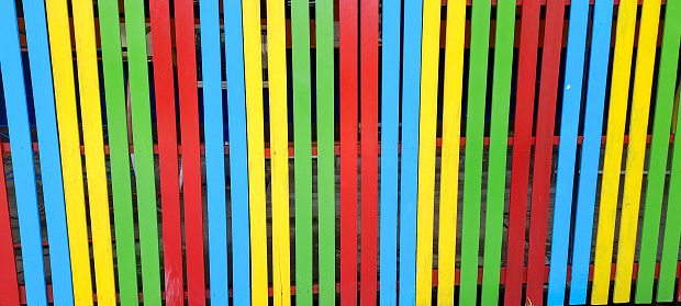 Multi colored rainbow wooden fence in garden background