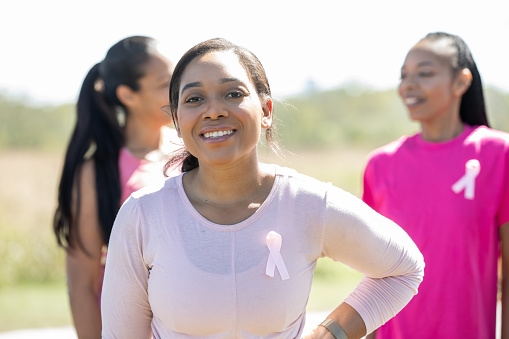 A joyful young woman attends a charity event for breast cancer awareness with diverse friends