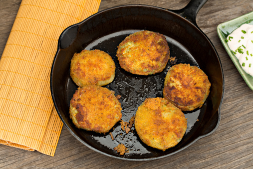 An overhead close up shot of fried green tomatoes in a black cast iron pan.