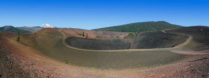 Panoramic view of the rim of the crater on top of Cinder Cone in Lassen Volcanic National Park with snow capped Mt Lassen in the background