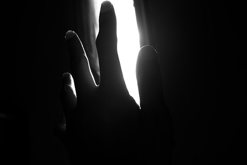 blocking the light in the window with the palm of the hand, the silhouette of the hand against the window light.