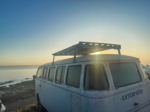 colonia del sacramento, uruguay - november 2 2022: a volkswagen van or bus parked at coast with sea or ocean sunset view