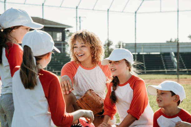 istock Co-ed Little League baseball features elementary-aged children as athletes, accompanied by coaches, on the ballfield 1751346894