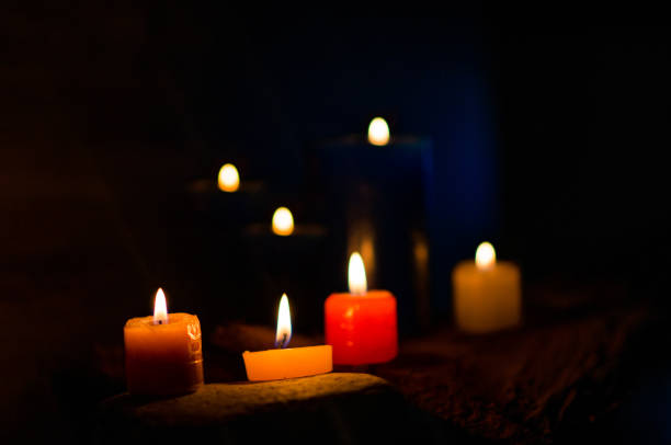 istock Colored candles burning on a black background and small light in the background 1751359041