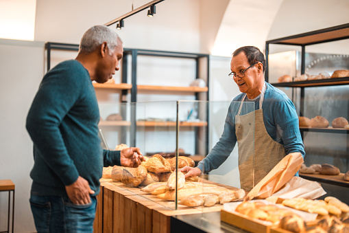 Mature Hispanic Male Buying Freshly Baked Goods In Small Artisan Bakery mature-hispanic-male-buying-freshly-baked-goods-in-small-artisan-bakery