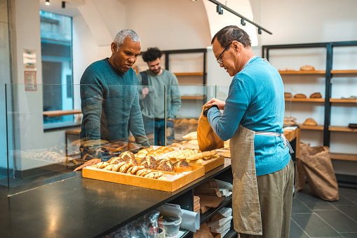 Mature Hispanic Male Buying Freshly Baked Goods In Small Artisan Bakery mature-hispanic-male-buying-freshly-baked-goods-in-small-artisan-bakery