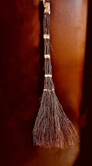 A large straw broom representing a witch’s broom hanging outside a Hoboken New Jersey apartment door to decorate and celebrate Halloween in October.