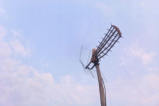 Jakarta, Indonesia - Oct 2023 : View of an antique antenna with a mast made of wood on a cloudy blue sky background.