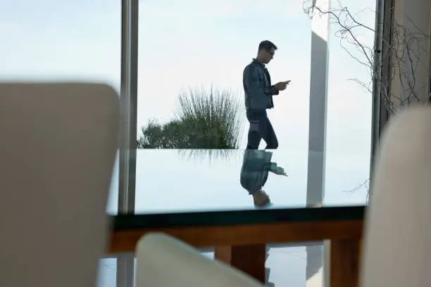 Photo of Businessman using cell phone at office window
