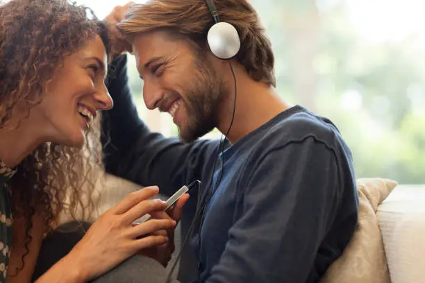 Photo of Couple listening to headphones on sofa