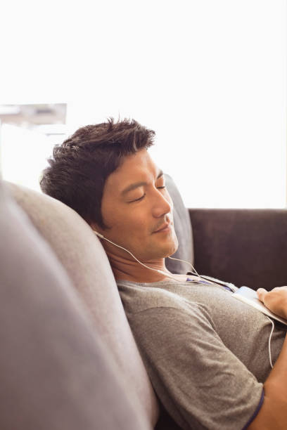 istock Man listening to headphones on sofa 175139009