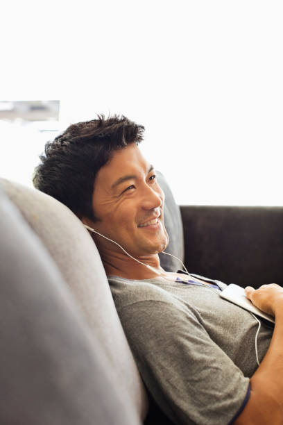 istock Man listening to headphones on sofa 175139034