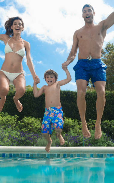 salto la familia en la piscina - swimming trunks bikini swimwear red fotografías e imágenes de stock