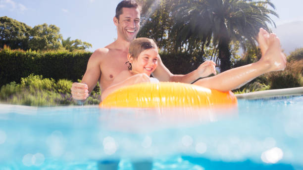 père et fils jouant dans la piscine - floatation device flash photos et images de collection