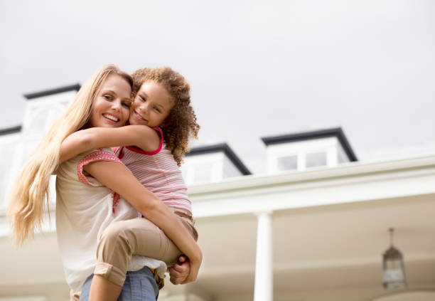 istock Mother and daughter hugging outside house 175139221