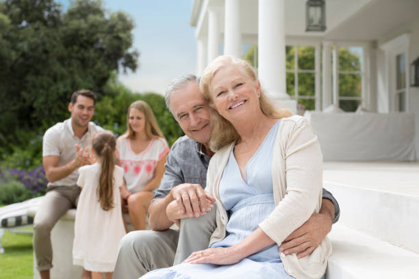 Caucasian couple wearing innovative prostheses, standing in back yard holding 3 year old daughter’s hand, and enjoying summer weather.