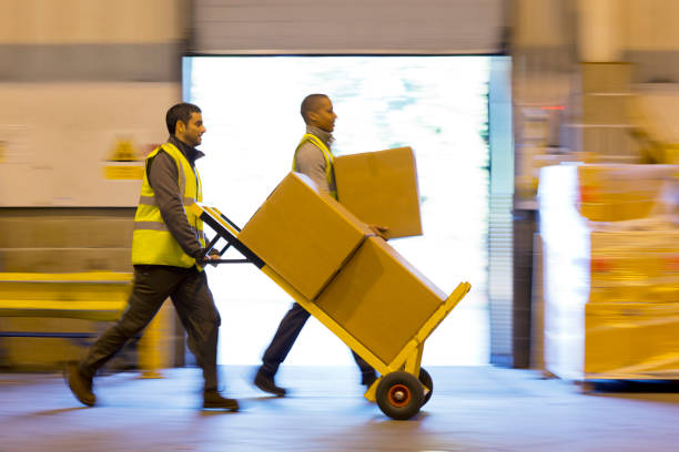 workers carting boxes in warehouse - hand truck 뉴스 사진 이미지