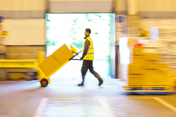 A moving company employee grimaces while lifting a box incorrectly. Adobe RGB color space.