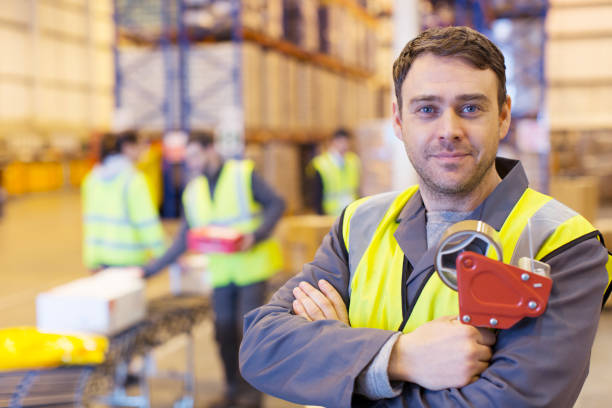 worker holding klebebandabroller im warehouse - warehouse worker stock-fotos und bilder