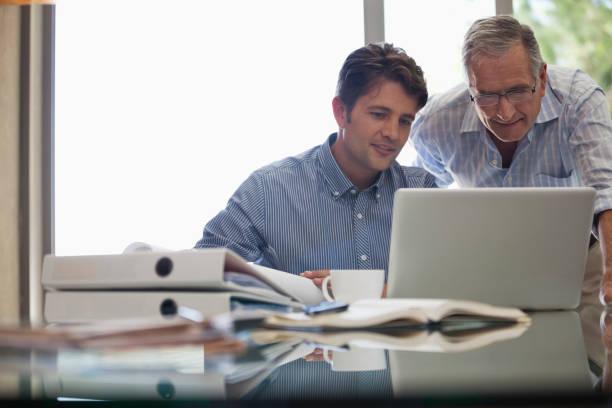 istock Older man and younger man working together at desk 175139907