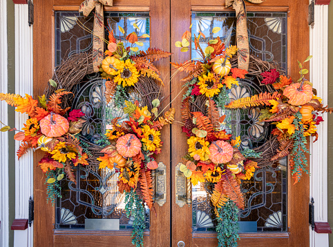 Fall wreath made up of colorful autumn leaves and pumpkins makes for a rustic look during the holiday season.