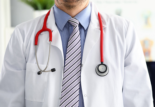 Stethoscope lying on male therapeutist doctor chest wearing necktie. Medical care help or insurance equipment shop or store concept. Physician waiting for patient to examine