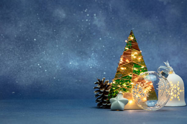 조명이 켜진 장난감과 푸른 흐릿한 배경에 빛나는 휴일 조명이 있는 전나무가 있는 크리스마스 장식. 스톡 사진