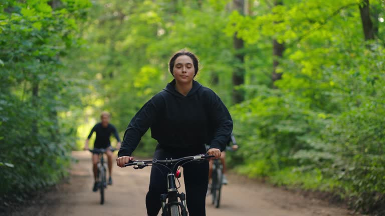 Intensive Cycling Workout In Forest, Young Women Riding Bikes In Nature, Frontal View