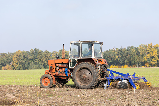The tractor uses discs to plow the soil after harvesting in the autumn.