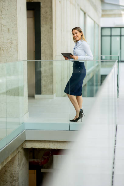 istock Young woman with digital tablet walking in the modern office hallway 1751564095