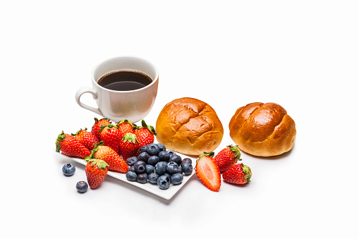 Homemade bread, fresh strawberries and berries with black coffee on a white background