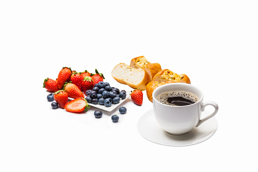 Homemade bread, fresh strawberries and berries with black coffee on a white background