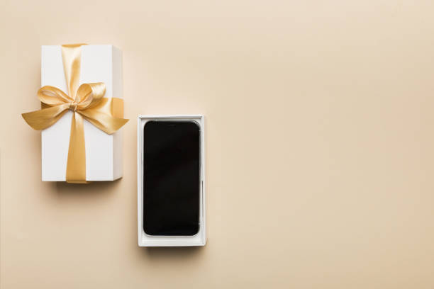 istock Opened gift box with gold ribbon and smartphone on color background, top view. Blank open box packaging mockup , Template for your design - branding mockup 1751572834