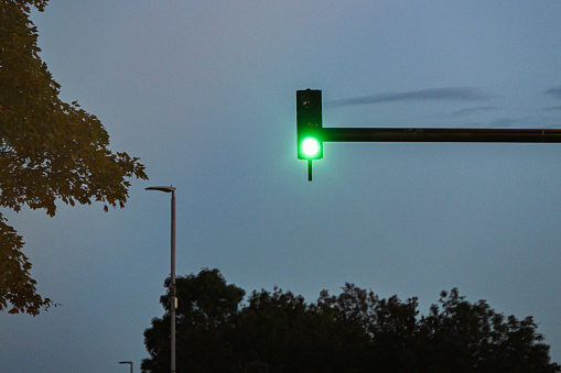 An overarching traffic light illuminating bright green, go sign for the oncoming traffic, traffic signal