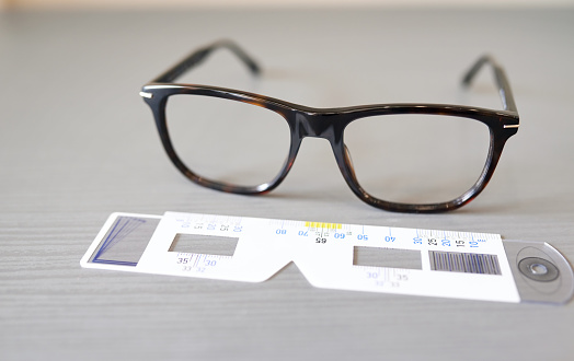 Hands, glasses and measuring frame with lens and vision, optometry and healthcare with choice and eye care background. Health, closeup of eyewear or spectacles in clinic with size and measurement