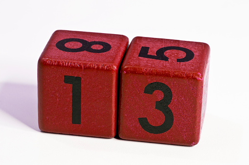 Number thirteen written on a red wooden cube of a calendar date.
