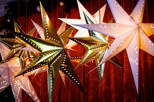 Decoration for holiday, glowing stars on red background. New year or Christmas holiday concept.