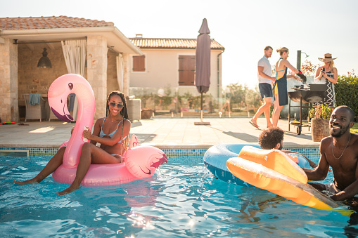 A group of diverse friends, accompanied by pool floats, soak up the sun and good times at a luxury villa pool party.
