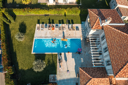 Drone shot. A joyful moment captured as friends take a dip at a vibrant villa pool party.
