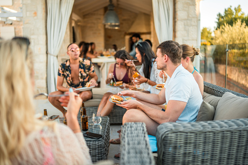 Friends enjoy a poolside meal and good company during a lively pool party.