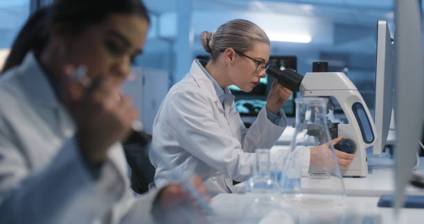 istock Scientists, test and lab with microscope for biotechnology, analysis and collaboration in research. Futuristic, laboratory and women working on science innovation for vaccine cure to virus or health 1751659731