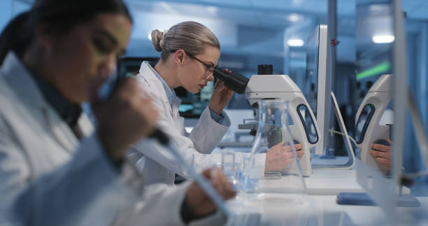 istock Scientists, lab and test with microscope for biotechnology, analysis and collaboration in research. Futuristic, laboratory and women working on science innovation for vaccine cure to virus or cancer 1751659735